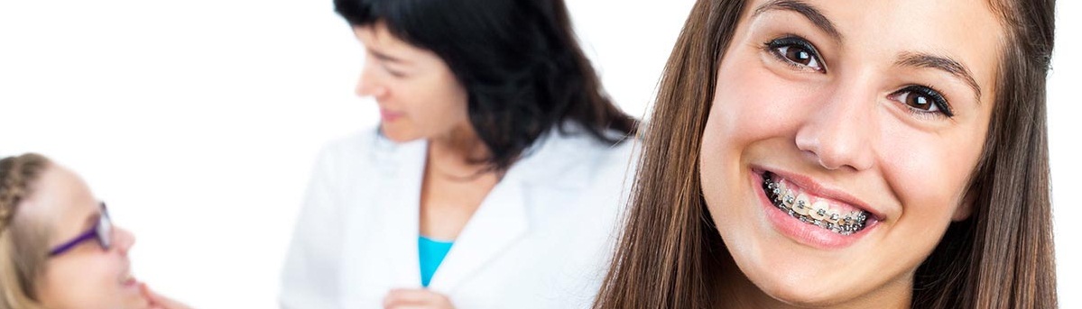 A woman happily displaying a tablet with a smiley face and dental brases on its screen, beside another dental checkup is going on.